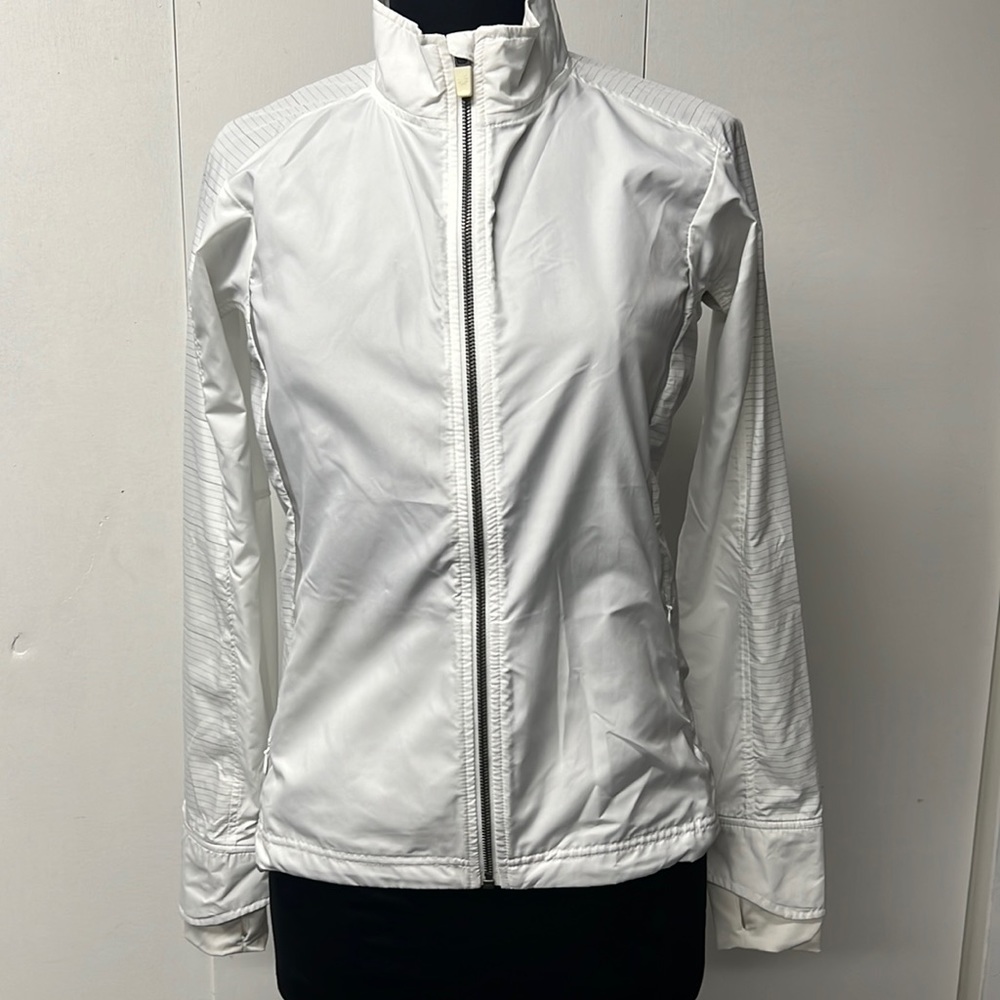 Athleta brand white lightweight jacket with reflective accents.